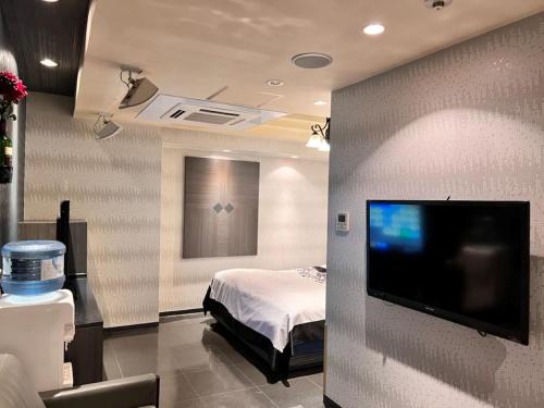 a bedroom with a bed and a flat screen tv at Hotel Opus -Adult only- in Kasugai