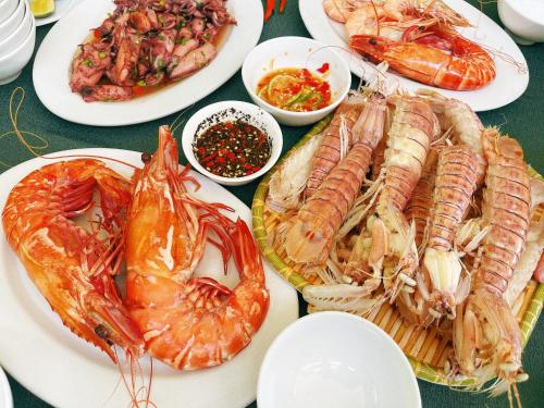 una mesa cubierta con platos de marisco y otros alimentos en Quy Phuong - Homestay, en Tân Hiệp