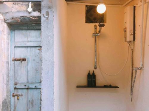 ein Badezimmer mit einer blauen Tür und einem Regal mit Flaschen in der Unterkunft Soo Hong (off Lebuh Armenian) penang heritage in George Town