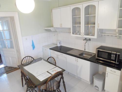a kitchen with white cabinets and a table with chairs at Garden 39 Vendégház in Szeged