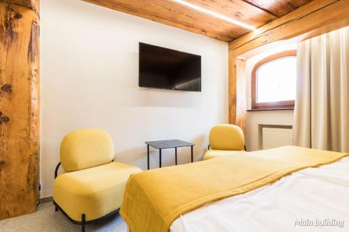 a room with two beds and two chairs and a tv at Hotel Spichrz in Toruń