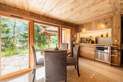 une cuisine avec une table et une grande fenêtre dans l'établissement Chalet Ananda avec Sauna, Baignoire Balnéo et Terrasse, à Chamonix-Mont-Blanc