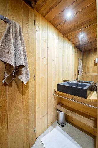 La salle de bains est pourvue d'un lavabo dans un mur en bois. dans l'établissement Chalet Ananda avec Sauna, Baignoire Balnéo et Terrasse, à Chamonix-Mont-Blanc