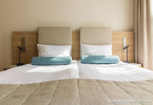 a bedroom with two beds with white and blue pillows at Hotel Spichrz in Toruń
