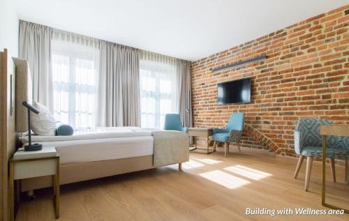 a bedroom with a bed and a brick wall at Hotel Spichrz in Toruń