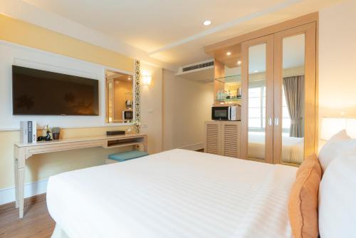 a bedroom with a white bed and a tv at La Petite Salil Sukhumvit Thonglor 1 in Bangkok