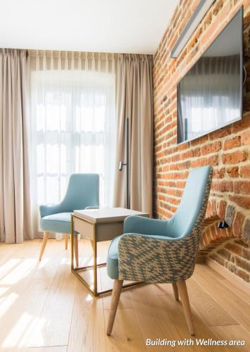 a living room with two chairs and a tv on a brick wall at Hotel Spichrz in Toruń