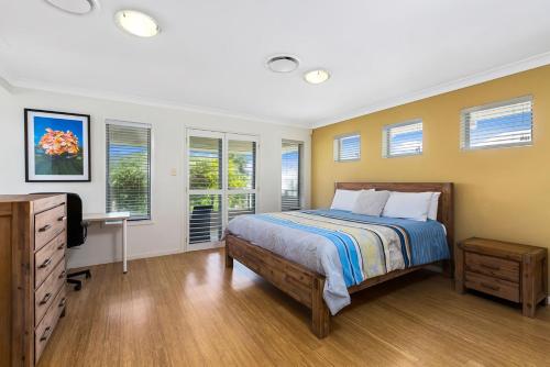 ein Schlafzimmer mit einem Bett, einem Schreibtisch und Fenstern in der Unterkunft Ocean Blue On Salt Beach in Kingscliff