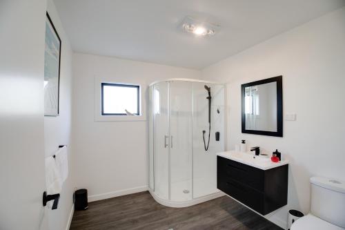 a white bathroom with a shower and a sink at Twin Camellias in Rotorua