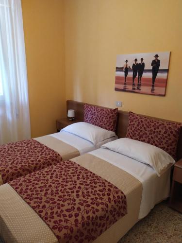 Albergo Grande Italia في مارينا دي بيتراسانتا: غرفة فندقية بسريرين ولوحة على الحائط