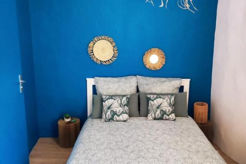 Un dormitorio con una pared azul y una cama con almohadas en Studio tout équipé au coeur de Aix en Provence, en Aix-en-Provence