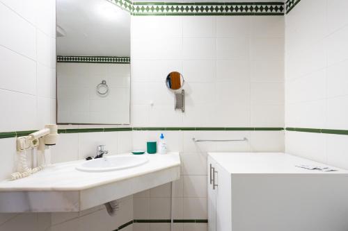 uma casa de banho branca com um lavatório e um espelho em 220 TROPICAL DUQUE Paradise by Sunkeyrents em Adeje
