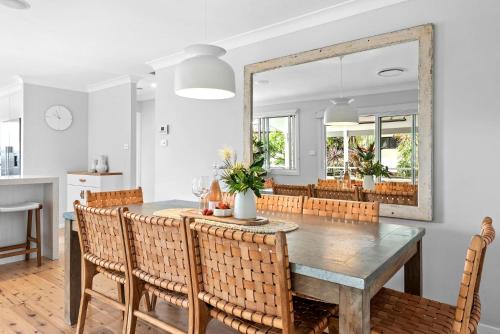 a dining room with a table and chairs and a mirror at Blue Lagoon Jervis Bay in Vincentia