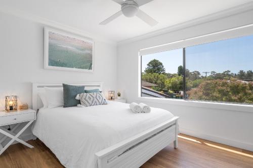 a bedroom with a white bed and a large window at Beauty By The Water in Chittaway Point