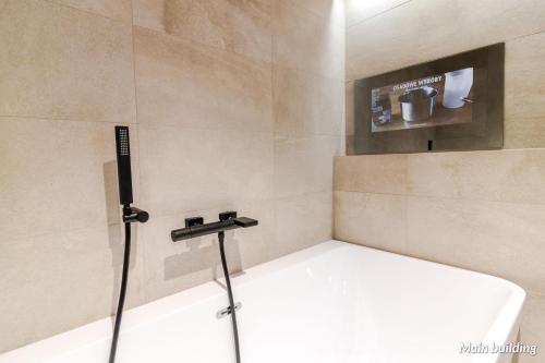 a bathroom with a bath tub with a sink at Hotel Spichrz in Toruń