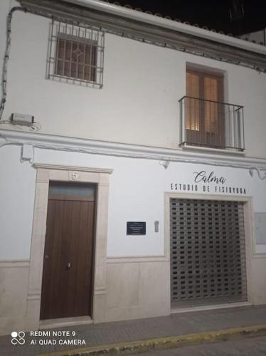 een wit gebouw met een bruine deur en twee ramen bij Elegante y acogedor. Buena ubicación in Osuna