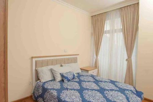 Un dormitorio con una cama azul y blanca y una ventana en Stunning Views Furnished apartment in Addis Ababa, en Addis Ababa