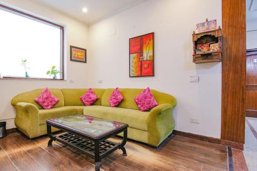 - un salon avec un canapé vert et des oreillers roses dans l'établissement SKS Excel Inn, à Gurgaon