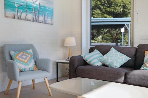 una sala de estar con un sofá y una silla en Calendo Apartments, en Merimbula