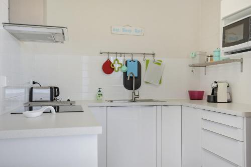 Una cocina blanca con gabinetes blancos y un fregadero. en Calendo Apartments, en Merimbula