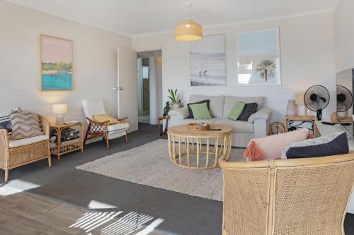 una sala de estar con un sofá y sillas en Calendo Apartments, en Merimbula