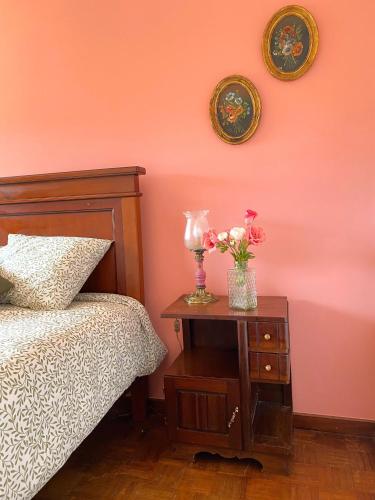a bedroom with a bed and a table with flowers on it at Villa do Sol Carcavelos Beach House in Carcavelos