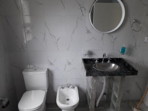 ein Badezimmer mit einem WC, einem Waschbecken und einem Spiegel in der Unterkunft COSTANERA Departamento in Strobel