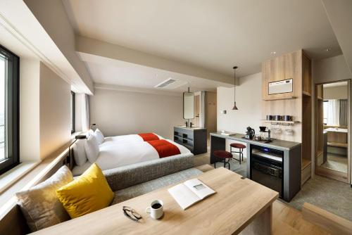 a bedroom with a bed and a desk and a kitchen at the b namba-kuromon in Osaka