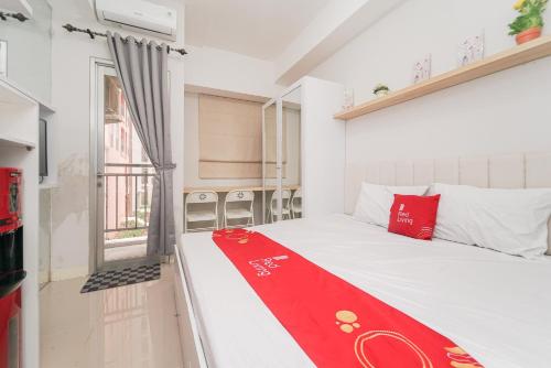 Una habitación con una cama con una manta roja. en RedLiving Apartemen Transpark Juanda - Frams Properti Tower Jade with Netflix, en Bekasi