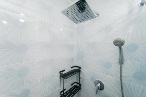 y baño con ducha y pared de azulejos blancos. en RedLiving Apartemen Transpark Juanda - Frams Properti Tower Jade with Netflix, en Bekasi