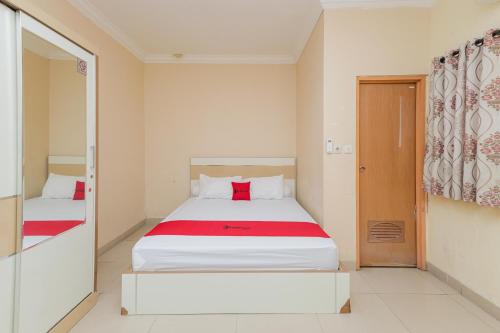 una camera con due letti con lenzuola rosse e bianche di RedDoorz Syariah near Stasiun Karet a Giacarta