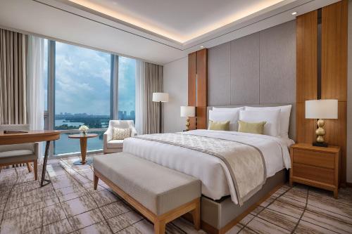 um quarto com uma cama grande, uma secretária e uma janela em LOTTE Hotel Yangon em Yangon