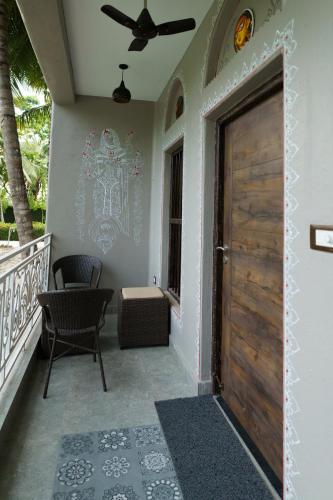 a porch with a wooden door and a chair at Breathing Earth - Rooms and Pool in Kolkata