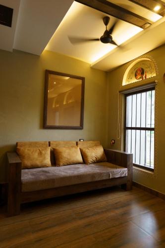 a couch in the corner of a room with a window at Breathing Earth - Rooms and Pool in Kolkata