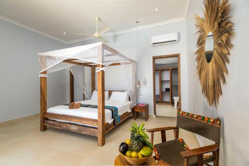 パジェにあるPaje Beach Apartments & Hotelのベッドルーム1室(天蓋付きベッド1台、フルーツボウル付)