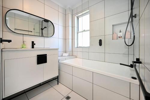 ein weißes Bad mit einer Badewanne und einem Spiegel in der Unterkunft Maroochydore 3 B/R, 2 Bath, Townhouse ZA4 in Maroochydore