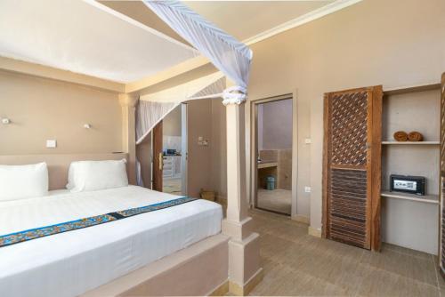 a bedroom with a large white bed and a window at Paje Beach Apartments & Hotel in Paje
