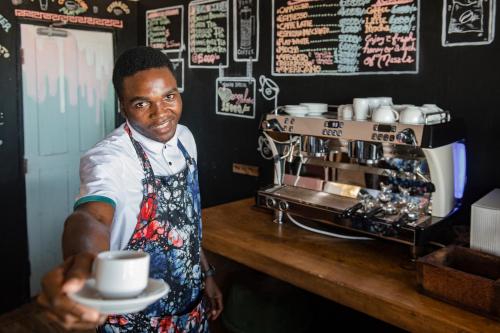 a man holding a cup of coffee in a coffee shop at Paje Beach Apartments & Hotel in Paje