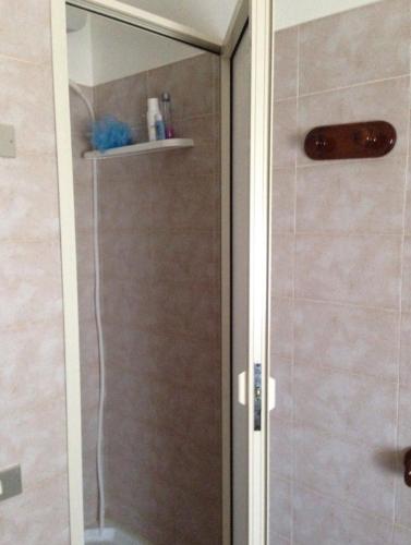 La salle de bains est pourvue d'une douche avec une porte en verre. dans l'établissement Sun bay apartment, à Agnone Bagni