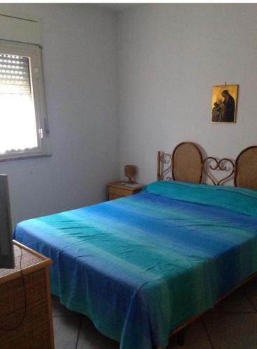 a bedroom with a blue bed with two chairs at Sun bay apartment in Agnone Bagni