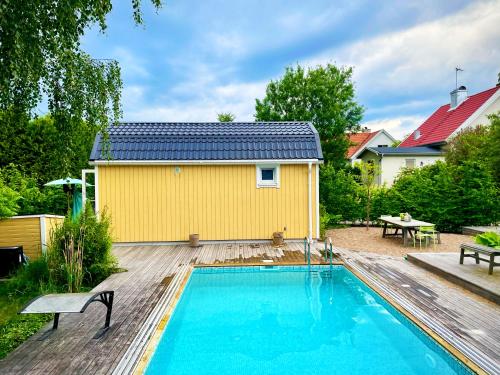 a yellow house with a swimming pool in a yard at Charming little country house in central Älmhult in Älmhult