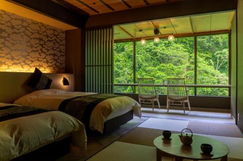 two beds in a room with a large window at Yamanakaonsen Ohanami Kyubei in Kaga