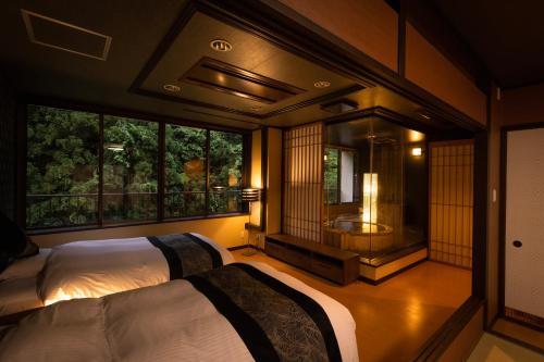 a bedroom with two beds and a bathroom with a tub at Yamanakaonsen Ohanami Kyubei in Kaga