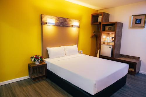 a bedroom with a white bed and a yellow wall at Hotel Sentral Kuantan @ Riverview City Centre in Kuantan