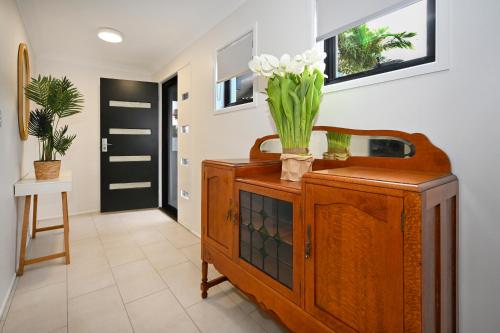 a room with a wooden cabinet with flowers on it at Lovely Beach House -Amazing Location, Pets - ZB9 in Buddina