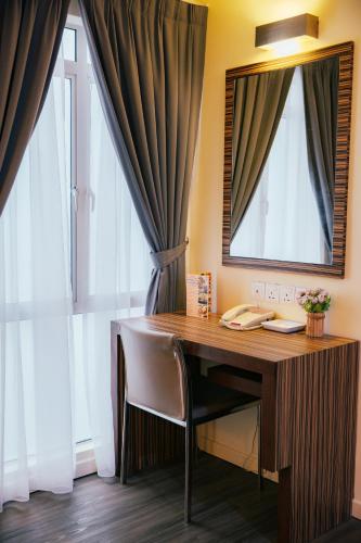 a desk in a room with a mirror and curtains at Hotel Sentral Kuantan @ Riverview City Centre in Kuantan