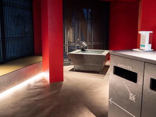 ELE Cabin Shinjuku Kabukicho في طوكيو: حمام مع حوض وجدار احمر