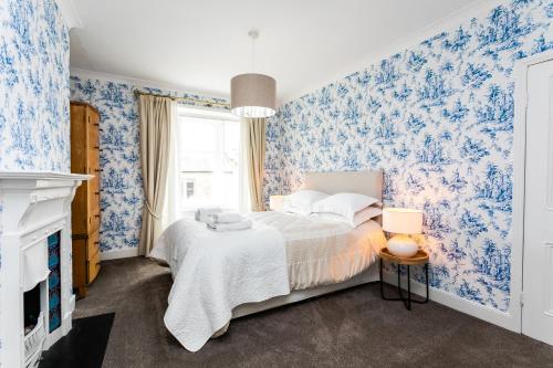 a bedroom with a bed with blue floral wallpaper at Westhill House in Warkworth