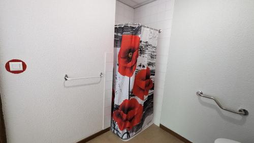 Saint-FloretにあるLes Lits des Féesのバスルームのドアに赤い花のシャワーカーテンが付いています。