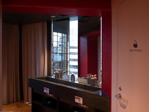 a bathroom with a sink with a large mirror at ELE Cabin Shinjuku Kabukicho in Tokyo